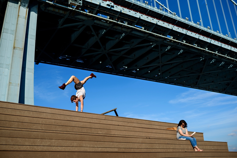 A woman doing a handstand under the Ben Franklin Bridge in philadelphia.